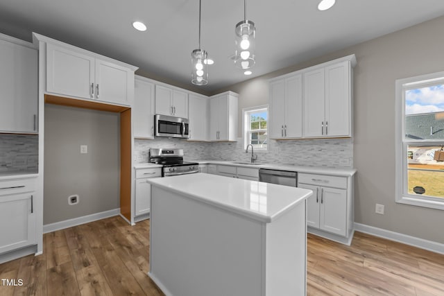 kitchen featuring pendant lighting, a center island, white cabinets, light wood-type flooring, and appliances with stainless steel finishes