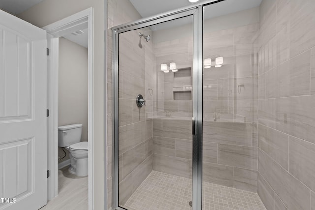 bathroom featuring hardwood / wood-style floors, an enclosed shower, and toilet