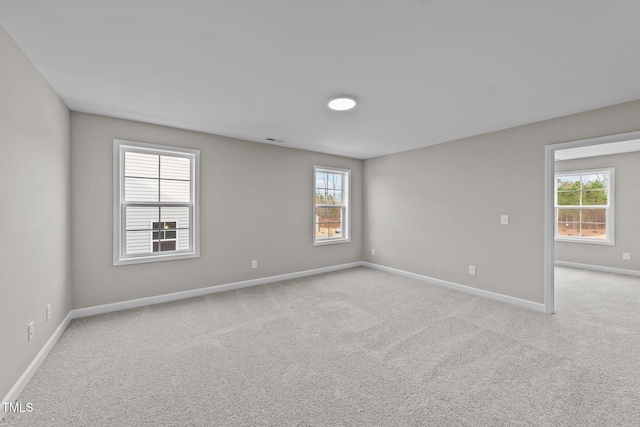 spare room featuring light carpet and a wealth of natural light