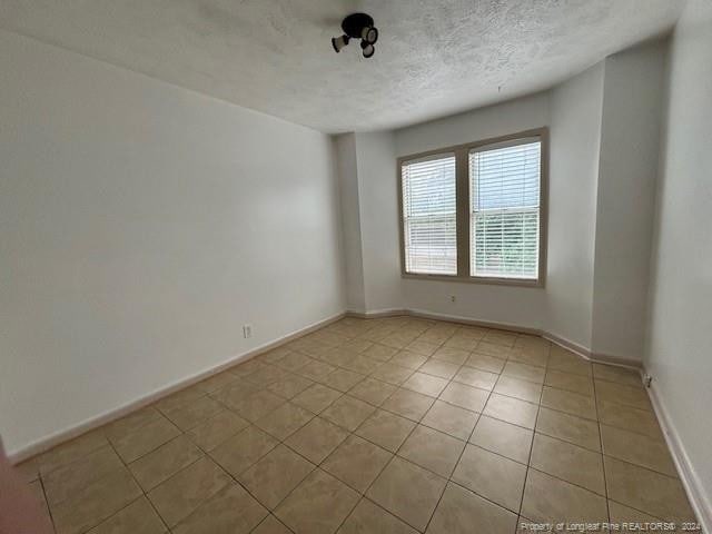 spare room featuring light tile patterned flooring and a textured ceiling