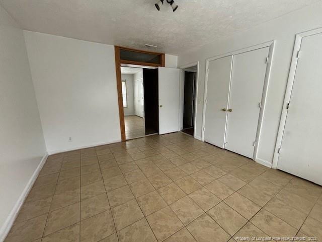 unfurnished bedroom with light tile patterned flooring and a textured ceiling