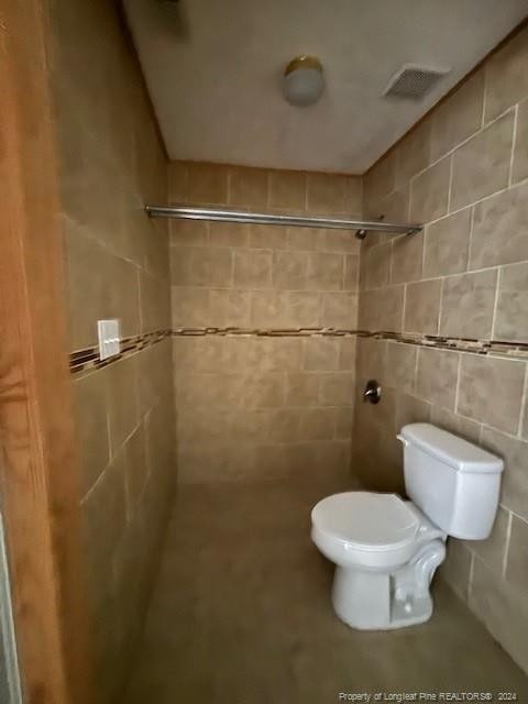 bathroom featuring a tile shower and toilet