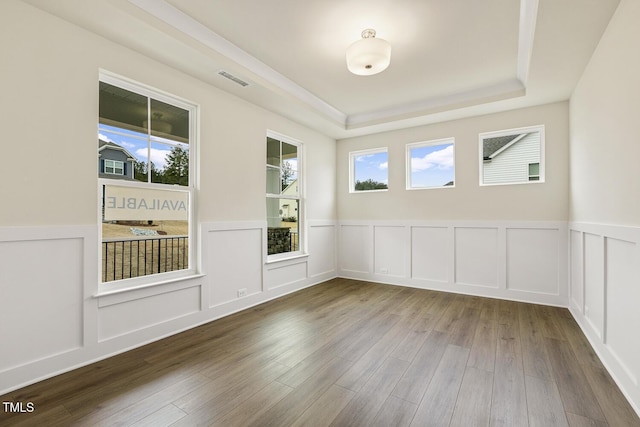 unfurnished room with hardwood / wood-style floors and a tray ceiling