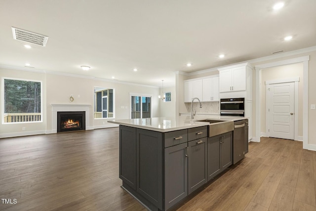 kitchen featuring white cabinetry, crown molding, dishwasher, oven, and a kitchen island with sink