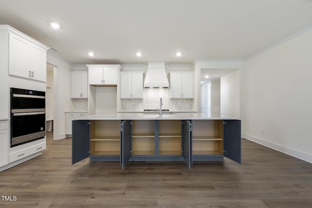 kitchen with premium range hood, a center island with sink, and white cabinets