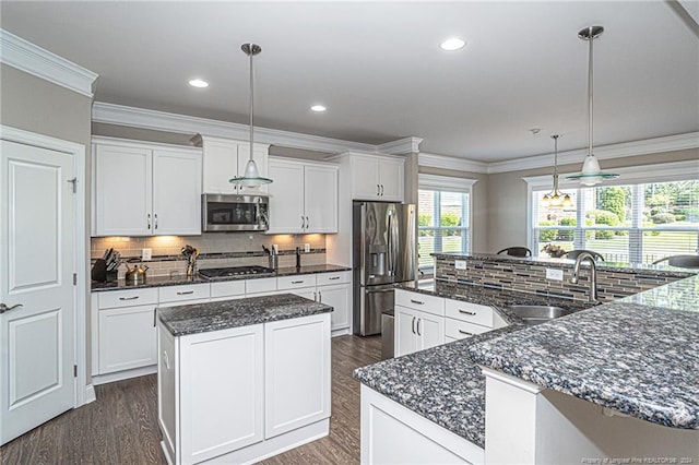 kitchen featuring white cabinetry, stainless steel appliances, decorative light fixtures, a kitchen island, and sink