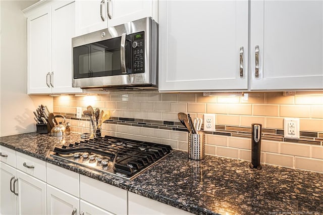 kitchen featuring backsplash, white cabinetry, appliances with stainless steel finishes, and dark stone countertops