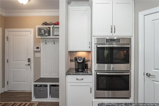 kitchen with tasteful backsplash, dark hardwood / wood-style flooring, white cabinets, double oven, and dark stone counters