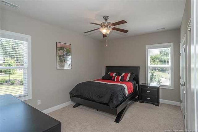 bedroom featuring ceiling fan, multiple windows, and light carpet