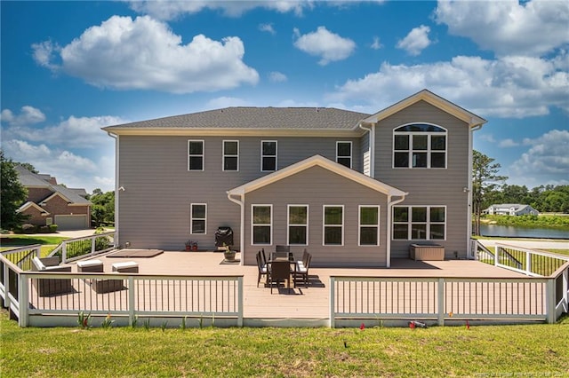 rear view of house featuring a deck with water view and a yard