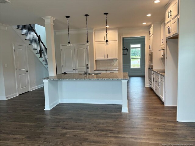 kitchen featuring an island with sink, light stone countertops, white cabinetry, and dark wood-type flooring