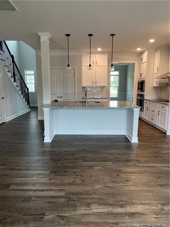 kitchen with white cabinetry, light stone countertops, oven, and hanging light fixtures