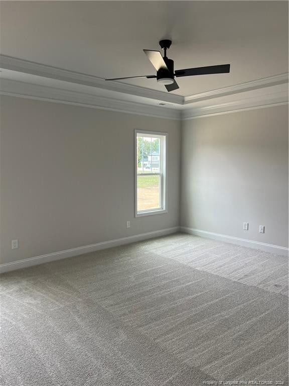 carpeted spare room featuring a raised ceiling, crown molding, and ceiling fan