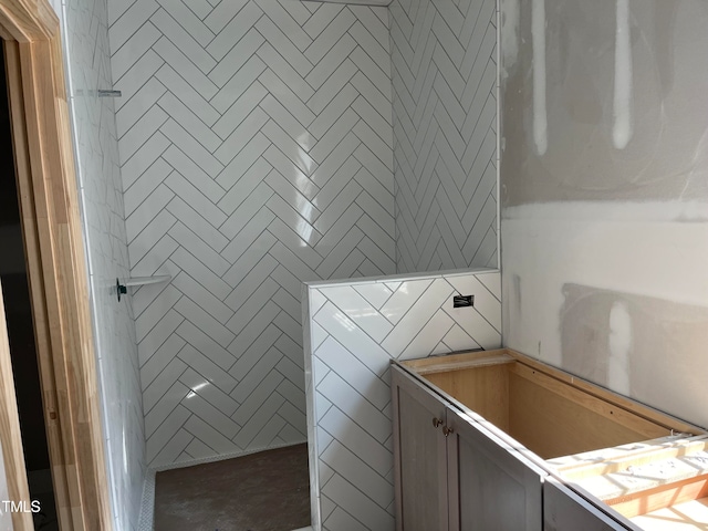 bathroom featuring a washtub and tile walls