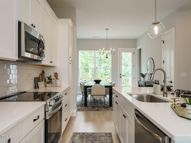 kitchen with stainless steel appliances, hanging light fixtures, sink, and white cabinets