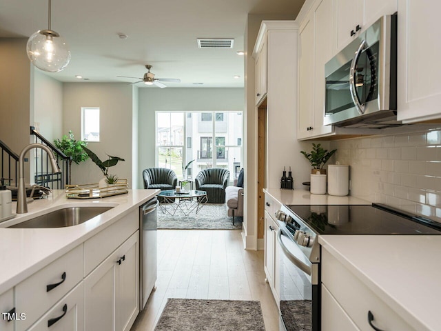 kitchen with sink, white cabinetry, decorative light fixtures, stainless steel appliances, and decorative backsplash