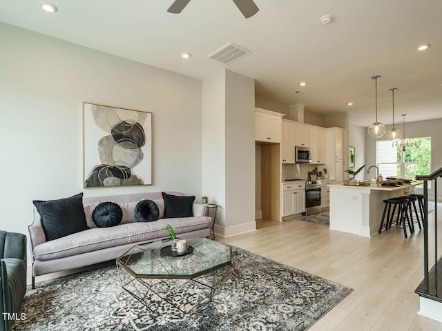 living room featuring ceiling fan and light wood-type flooring