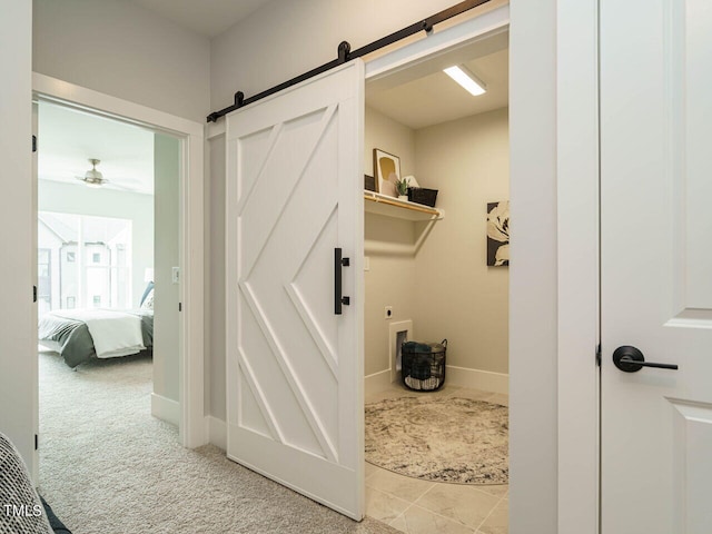 interior space with a barn door, hookup for an electric dryer, light carpet, and ceiling fan