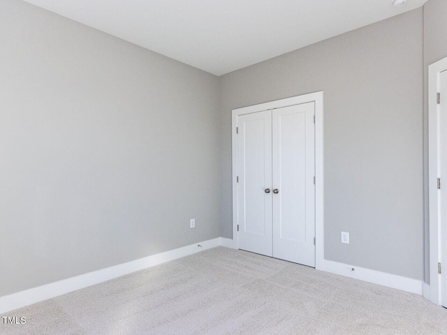 unfurnished bedroom with light carpet and a closet