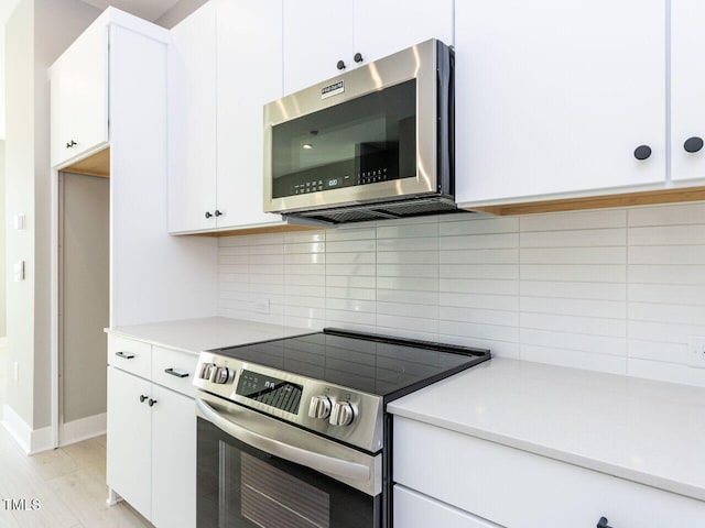 kitchen with stainless steel appliances, decorative backsplash, and white cabinets