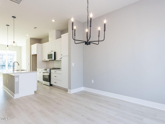 kitchen featuring pendant lighting, sink, white cabinetry, stainless steel appliances, and an island with sink