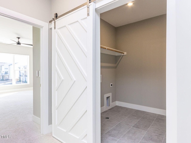 laundry room with a barn door, carpet floors, hookup for an electric dryer, and ceiling fan