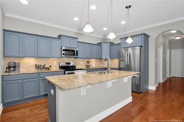 kitchen with sink, dark wood-type flooring, an island with sink, decorative light fixtures, and appliances with stainless steel finishes