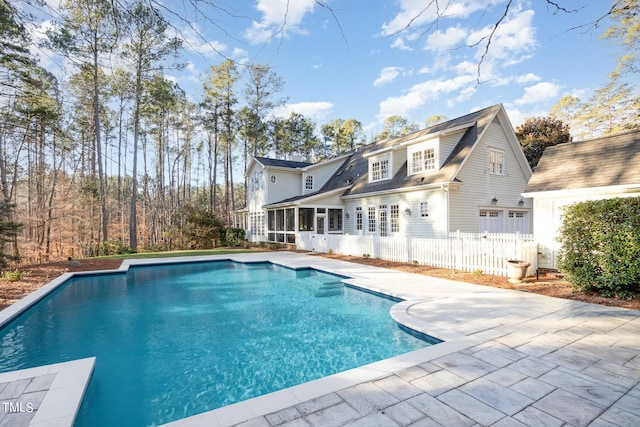 back of house with a fenced in pool, a sunroom, and a garage