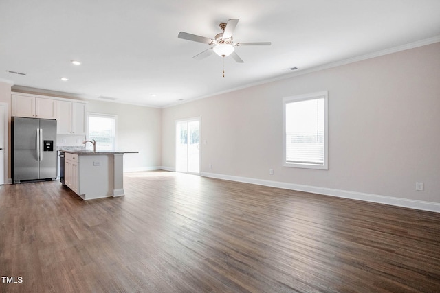 kitchen featuring white cabinets, appliances with stainless steel finishes, dark wood-type flooring, and an island with sink