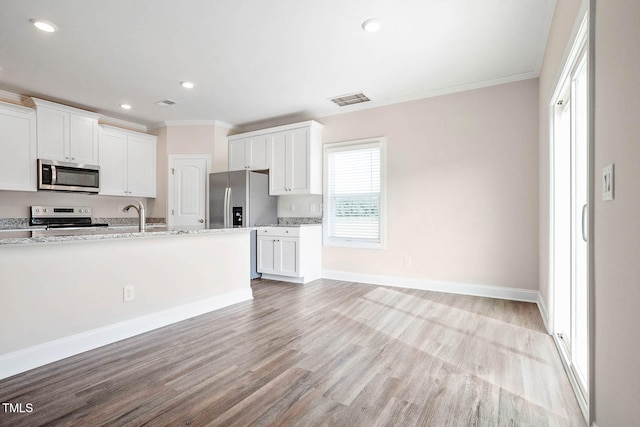 kitchen featuring crown molding, light hardwood / wood-style floors, light stone counters, white cabinetry, and stainless steel appliances