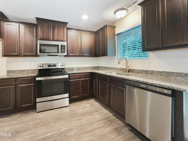 kitchen featuring dark brown cabinetry, sink, light hardwood / wood-style flooring, and appliances with stainless steel finishes