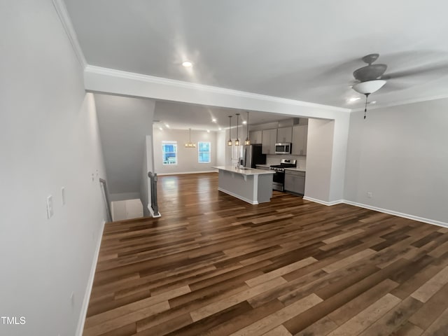 unfurnished living room featuring ornamental molding, ceiling fan with notable chandelier, and dark wood-type flooring