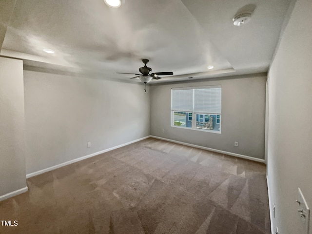 spare room featuring a tray ceiling, ceiling fan, and carpet