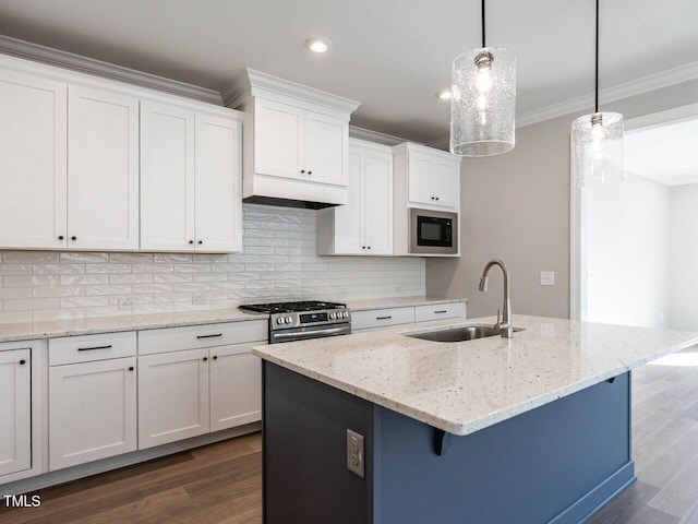 kitchen with a kitchen island with sink, black microwave, hanging light fixtures, and gas range