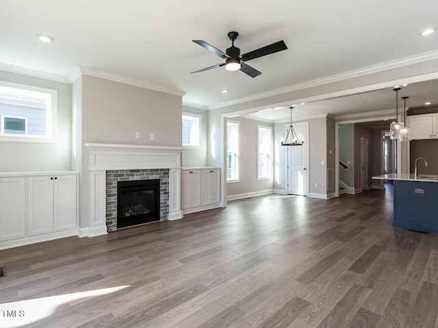 unfurnished living room featuring dark hardwood / wood-style flooring, a brick fireplace, ornamental molding, and sink