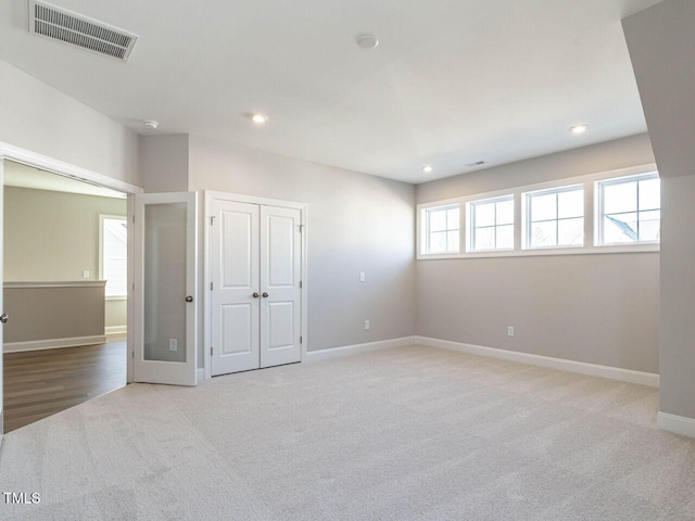 spare room featuring french doors and light colored carpet