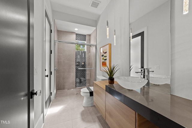 bathroom with tile patterned flooring, vanity, toilet, and a shower with door