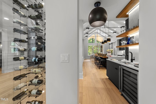 wine cellar with light wood-type flooring, wet bar, and beverage cooler