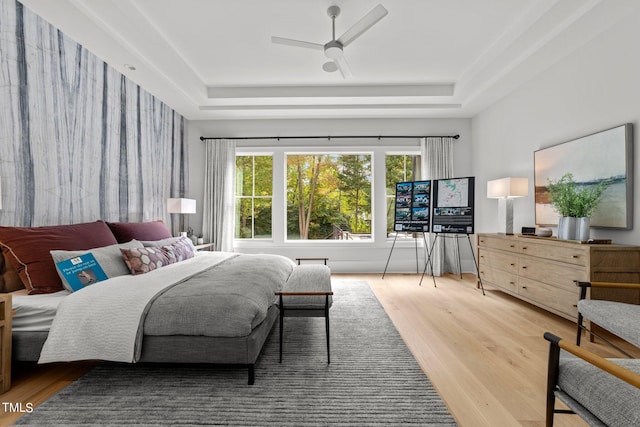 bedroom featuring a raised ceiling, hardwood / wood-style floors, and ceiling fan