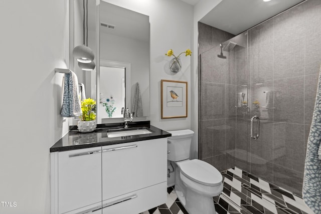 bathroom with vanity, tile patterned flooring, toilet, and an enclosed shower