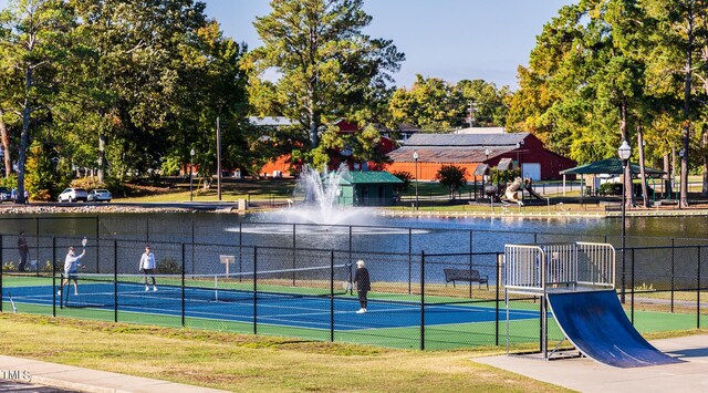 view of tennis court with a water view