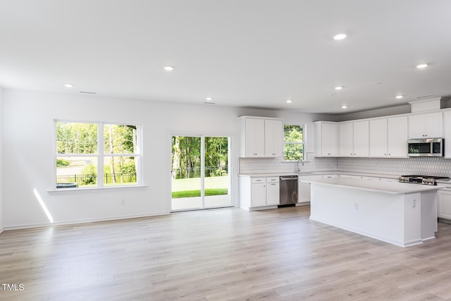 kitchen with sink, a center island, light wood-type flooring, appliances with stainless steel finishes, and white cabinets