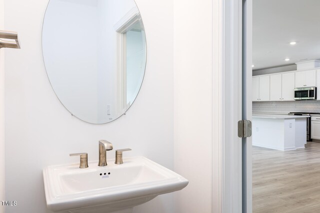 bathroom featuring hardwood / wood-style flooring, sink, and backsplash