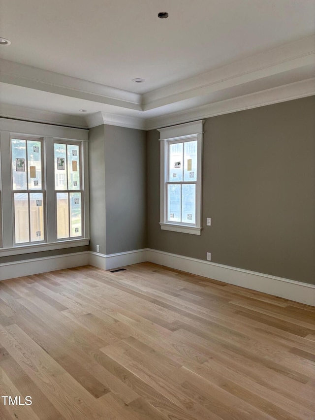 8305 Society Pl, Raleigh, NC 27615 - empty room featuring light wood-style floors, baseboards, a tray ceiling, and ornamental molding