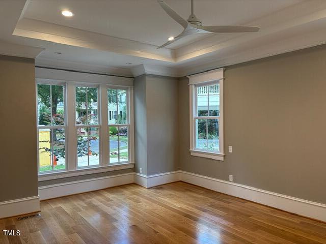 8305 Society Pl, Raleigh, NC 27615 - spare room with a tray ceiling, ceiling fan, wood finished floors, crown molding, and recessed lighting