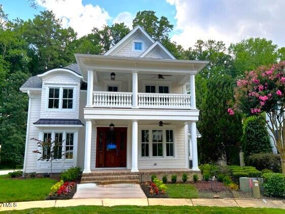 8305 Society Pl, Raleigh, NC 27615 - greek revival house with a balcony, a ceiling fan, covered porch, and a front lawn