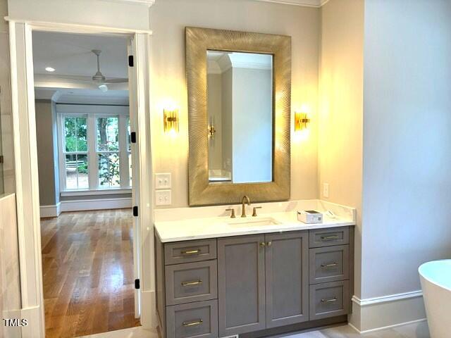 8305 Society Pl, Raleigh, NC 27615 - full bathroom featuring vanity, a freestanding tub, ornamental molding, and wood finished floors