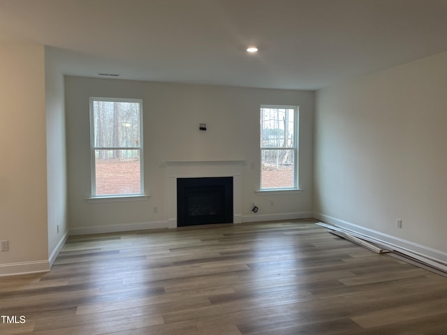 unfurnished living room featuring wood-type flooring and a wealth of natural light