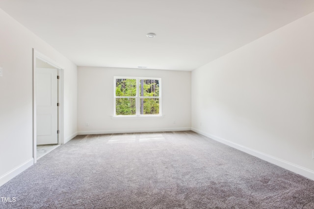 carpeted empty room featuring baseboards