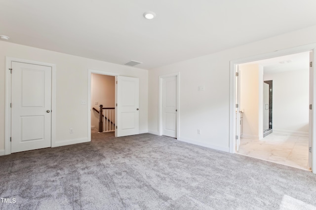 unfurnished bedroom with carpet floors, baseboards, and visible vents